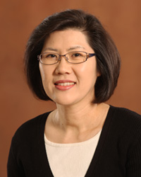 Choon Lee in a white blouse and black sweater smiling at the camera.