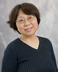 Bingbing Li in a dark sweater and glasses smiling at the camera.