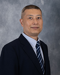 A man wearing a suit coat, collared shirt and tie poses for a headshot.