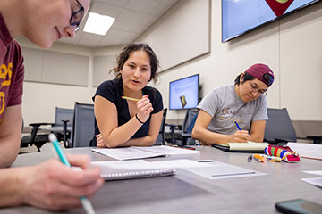 Three mathematics student collaborating on a problem in an active learning classroom.