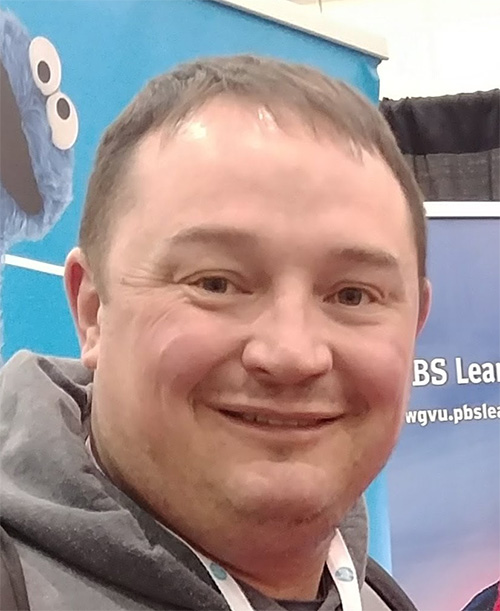 20250711_Sean A man with short hair standing in front of a banner with cookie monster on it.