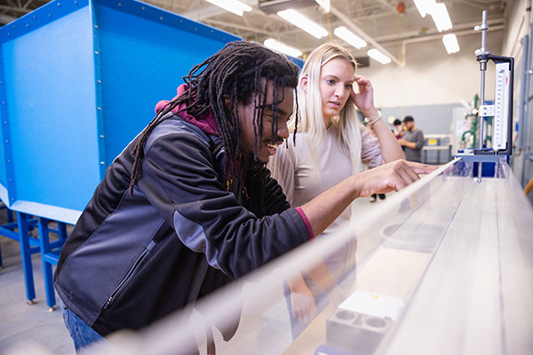 Two students examining results from water displacement experiment in environmental engineering lab.