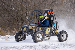 A student driving a CMU Baja vehicle in the snow.