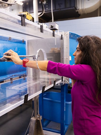 A student placing a car model into a wind tunnel.