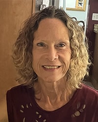 Headshot of Kari Leikert with curly hair smiling.