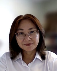 Professional headshot of Nailya DeLellis wearing white against a blurred background.