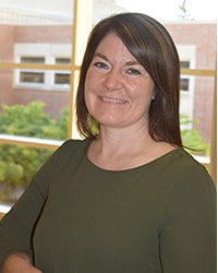 AnnMarie Bates wears an olive green sweater while looking at the camera.