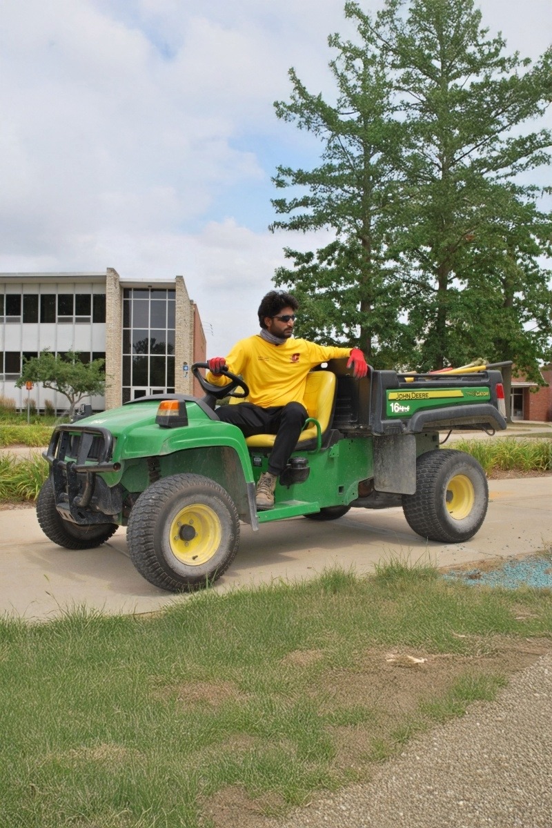 Landscape Student Employee sits on John Deere gator
