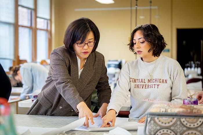 Sewing-700x467 A faculty member works with a student in the fashion lab reviewing design plans.