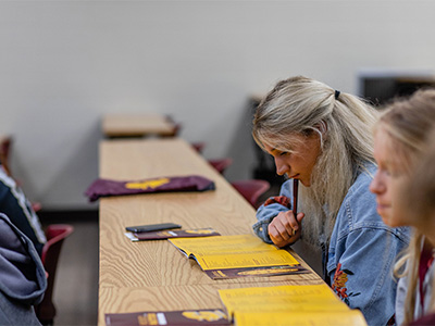 A student sits at a desk with a brochure in front of her at orientation.