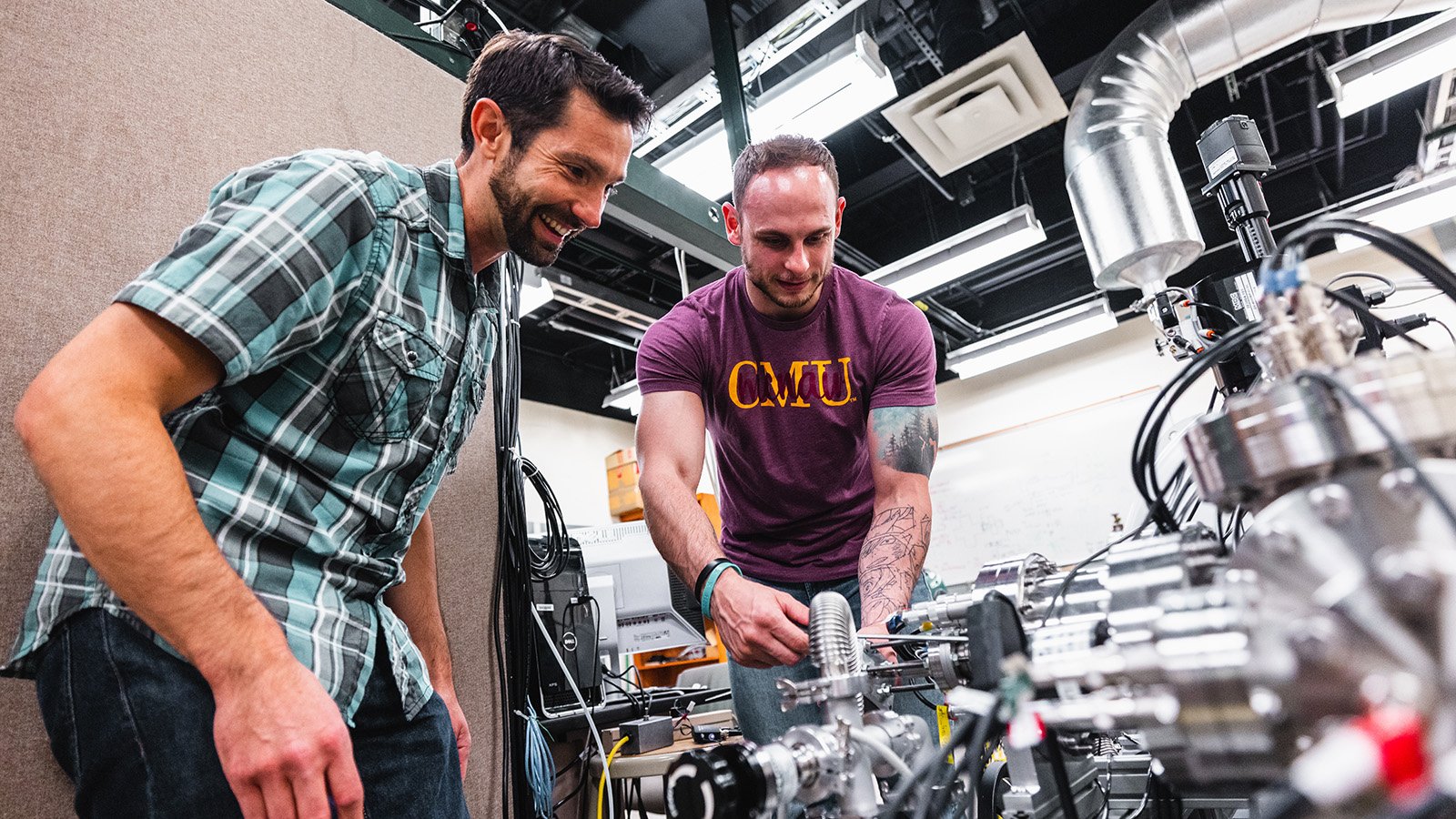 Lift_Scholarship A male faculty with dark hair and a male student in a maroon shirt working on a research project.