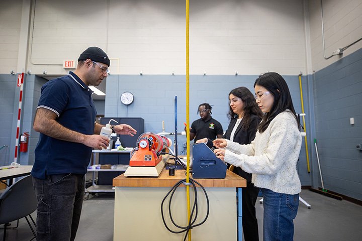 Four engineering students stand around a table in an engineering lab.
