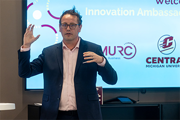 A man in a suit standing in front of a screen.
