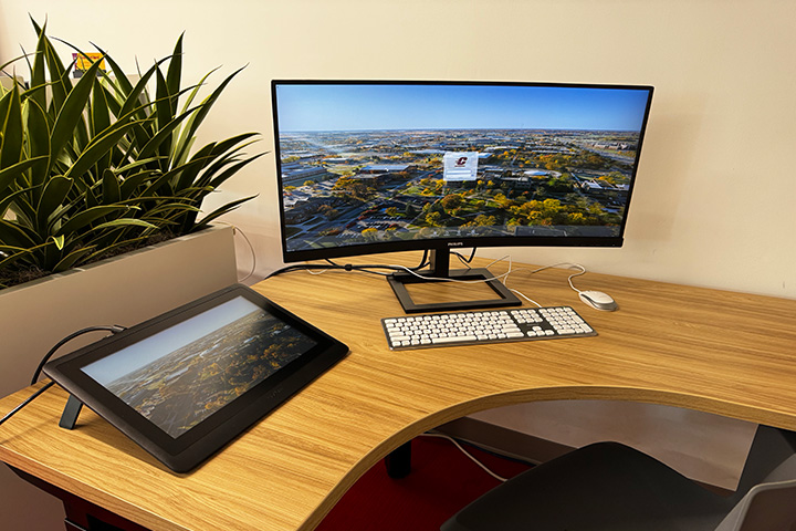 A computer screen and a keyboard on a desk