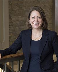 A woman in a dark blazer smiles at the camera