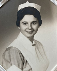 A black and white image of a dark haired woman in a nurse uniform