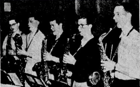 Black and white photo of a group of people playing saxophones.