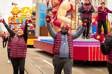 A man and woman waving and walking in a parade.
