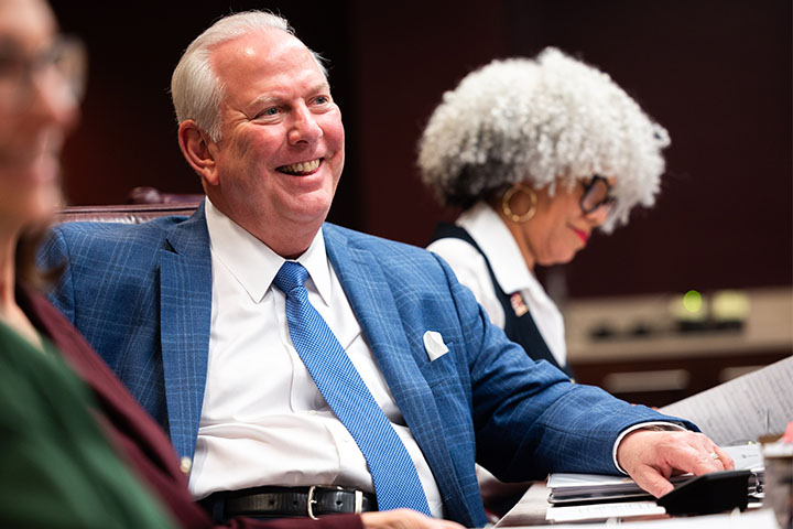 A man in a blue suit and tie smiling.