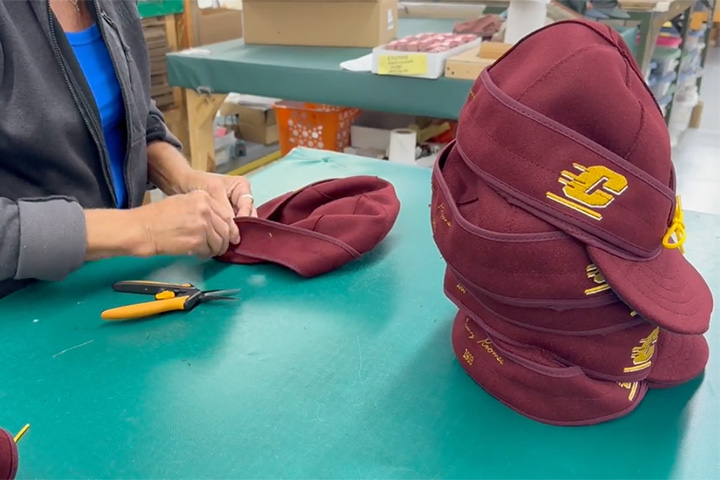 A person making a maroon CMU hat