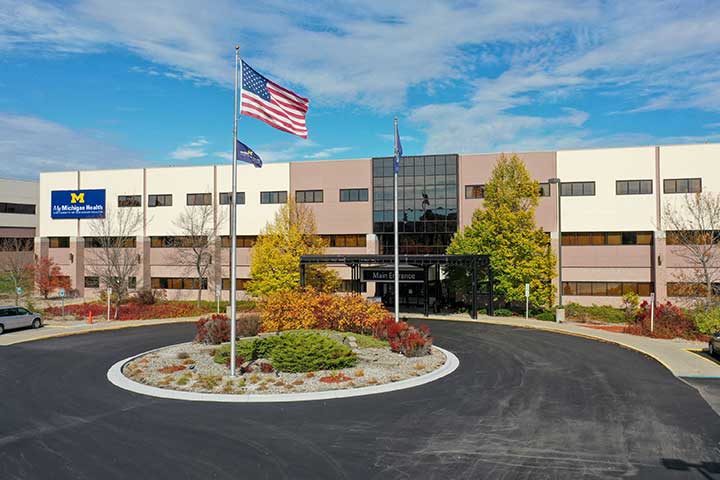 An exterior photo of a multistory medical center building with a paved parking area in the front