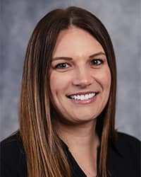Cecily Barnaud, Student Athlete Dedicated Counselor profile portrait, smiling, wearing a black top with a grey background