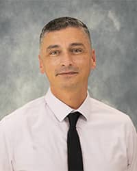 Profile Picture of Kevin Vaillancourt, Counselor, Wearing a light pink dress shirt with dark tie with a grey background