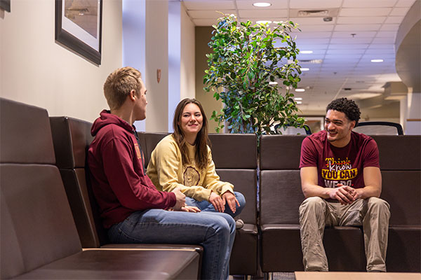 A group of students sitting on a couch in a residence hall.