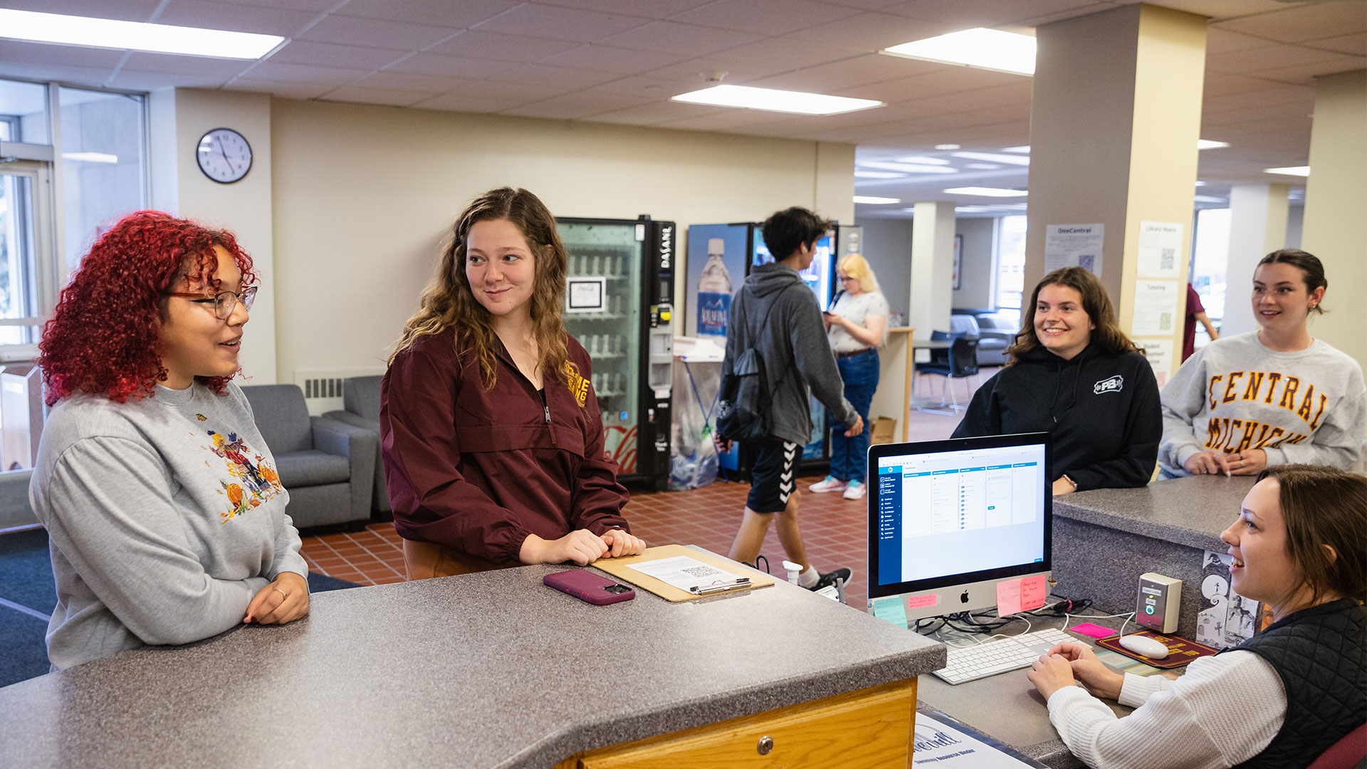 SweeneyFrontDesk_1920x1080 Students talking to residence life coordinator at the front desk of Sweeney Hall.