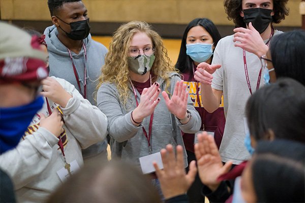 Group of students in a circle working through a team building activity.
