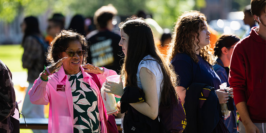 A female faculty member speaking to students at an event. 