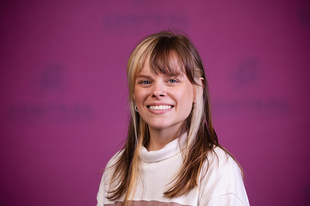 Professional headshot of Ayla Sisco wearing a maroon and white shirt while looking at the camera.