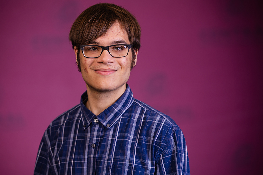 Professional headshot of Devere Edwards wearing a blue and white striped button down shirt while looking at the camera.