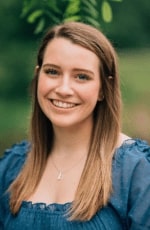 A woman standing outside and smiling for a professional headshot.