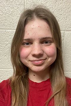 A headshot of SI Leader, Lucille Nobis, posing in front of a white wall.