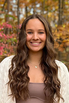 MadisonTravisforWeb A photo of SI Leader, Madison Travis, posing outdoors in front of colorful fall foliage