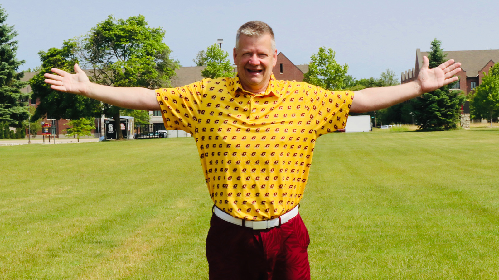 TO 1600x900 for TO story A man wearing a yellow polo and maroon shorts stands with his arms spread out.