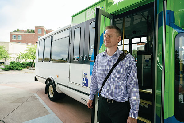 CMU alum dressed in business attire walking off of BATA bus.