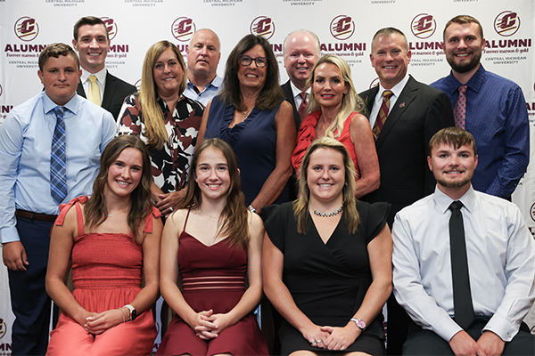 A group of people posing for a photo in front of an Action C backdrop.