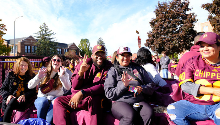 Central Michigan University alumni board members dressed in maroon and gold on a float during the CMU homecoming parade.