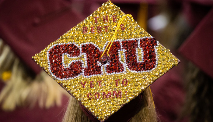 A CMU graduate wearing a decorated graduation cap with sparkling letters and text.