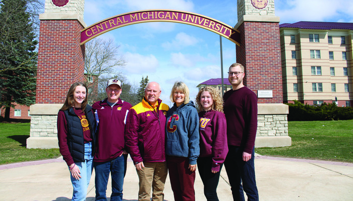 The Voisin family poses in front of the Central Michigan University arch wearing CMU gear.