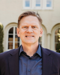 A man in a suit smiles for a photo.