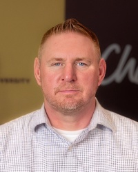 a man with short hair wearing a white collared shirt.