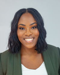 A woman in a blazer smiling for a photo.