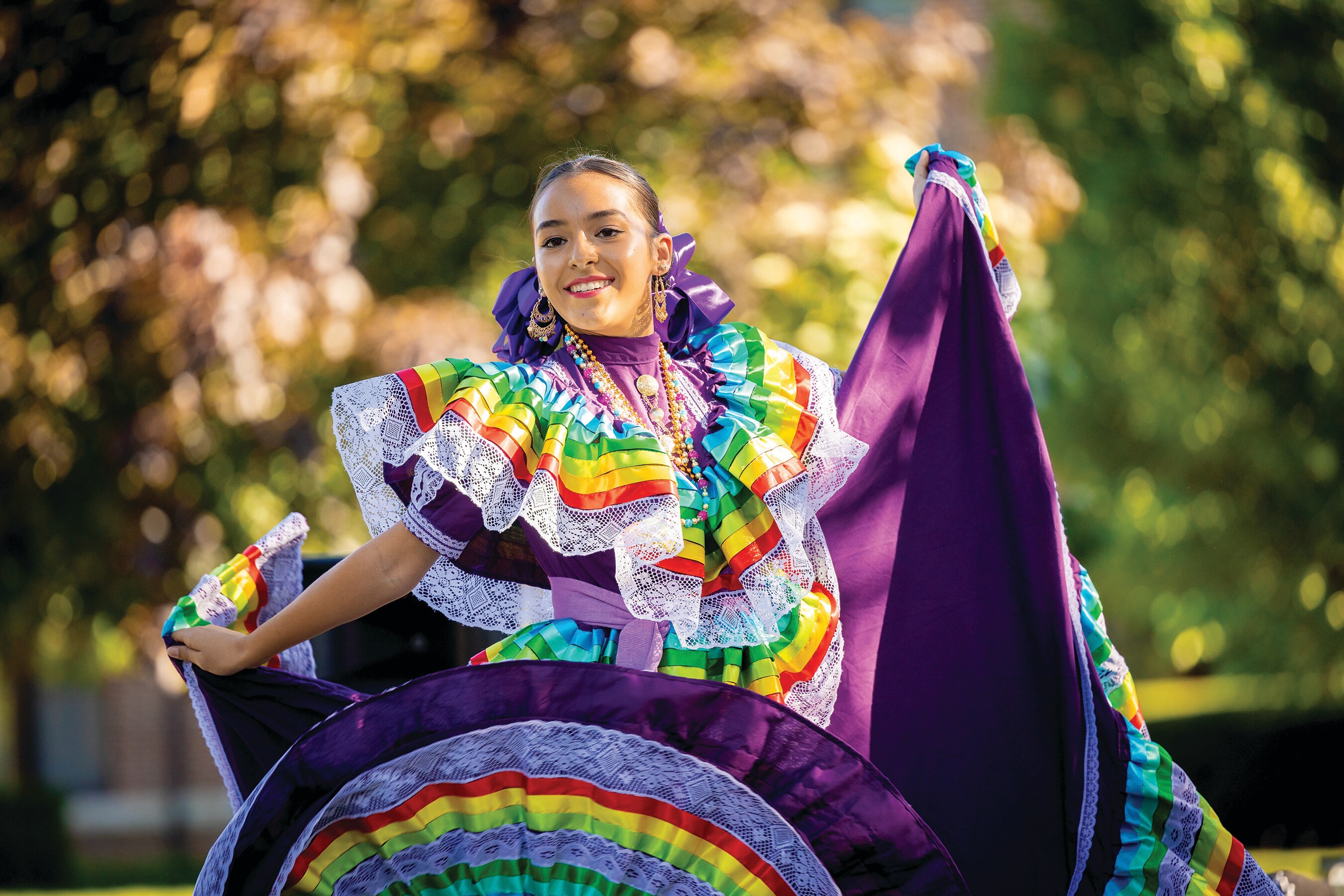 A woman in a colorful dress is dancing outdoors.