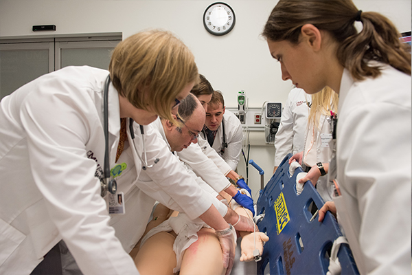 Doctors and residents moving a patient from a back board to a gurney.